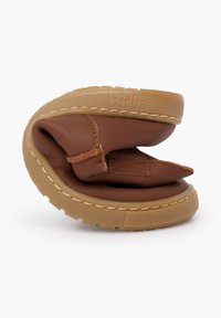 Hnědá kožená bota s měkkým materiálem, zaobleným tvarem, flexibilním designem a béžovou gumovou podrážkou. Výrazná svou skládací konstrukcí.