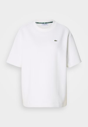 Weißes Kurzarm-T-Shirt von Lacoste mit Rundhalsausschnitt und kleinem grünen Krokodil-Logo auf der linken Brust.
