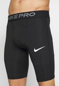 Svarta Nike Pro kompressionstights som bärs på en manlig överkropp, med en vit Nike swoosh på låret och en märkesresår.