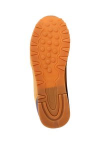 Suela de zapato con una superficie de goma naranja texturizada que presenta patrones circulares y estrías para mayor agarre, que se transforma en una parte superior de color azul oscuro.