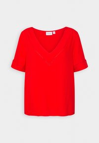 Blouse rouge à manches courtes avec un col en V, présentant un détail de couture décorative le long du col et des poignets de manches. Texture lisse.
