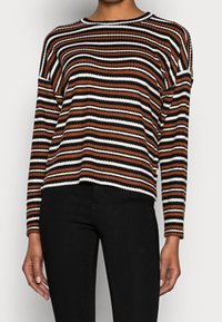 Randig tröja i brunt, svart och vitt. Ribbad textur, långa ärmar, rund halsringning, lös passform och något kortad fåll.