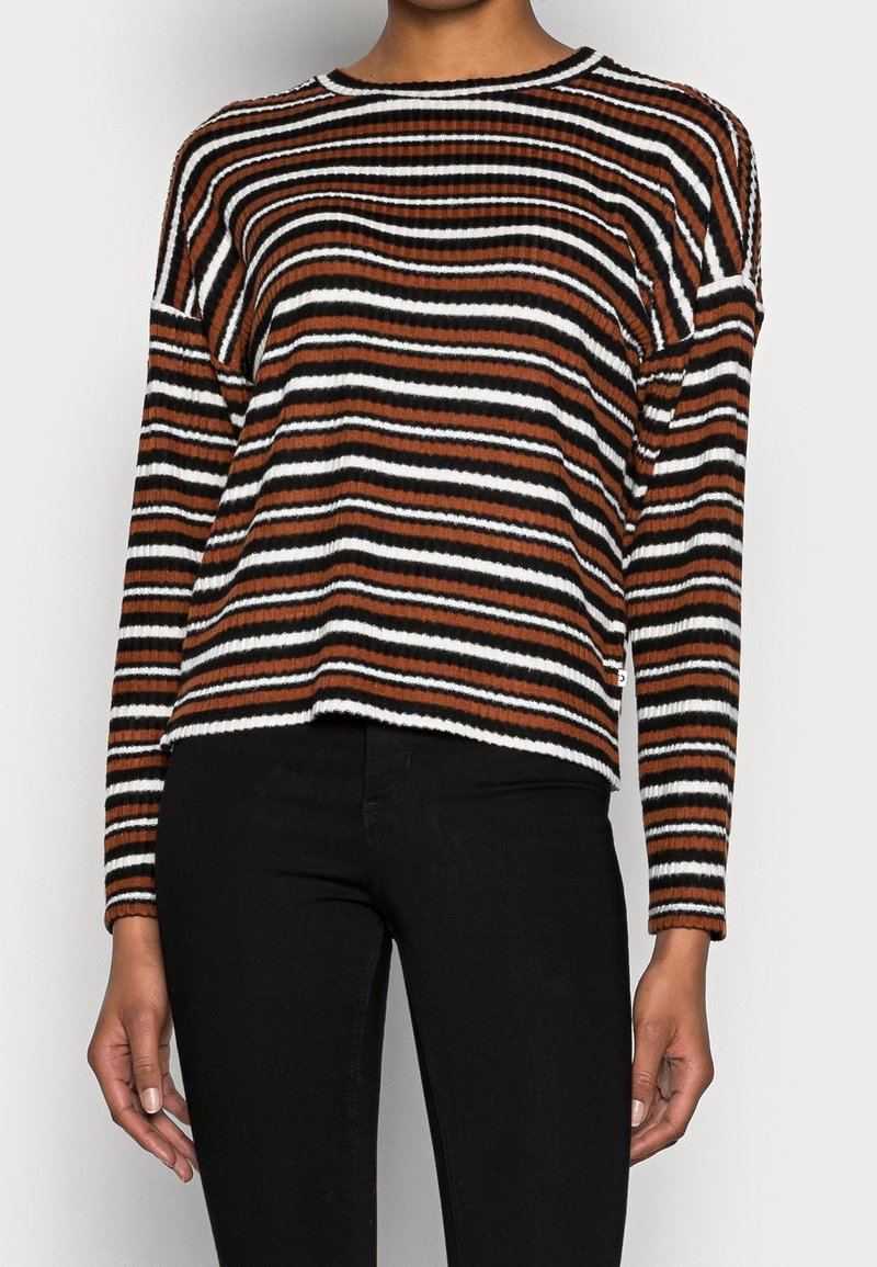 Randig tröja i brunt, svart och vitt. Ribbad textur, långa ärmar, rund halsringning, lös passform och något kortad fåll.