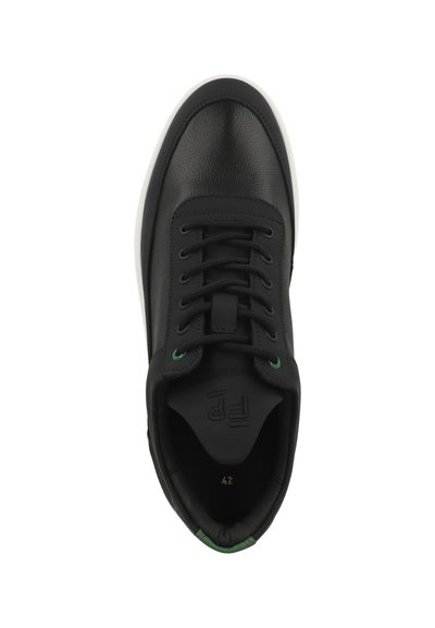 Svart lädersneaker med en strukturerad yta, som har en vit sula, gröna detaljer på ögonen och en märkesetikett på tungan.