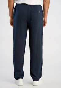 Marineblauwe joggingbroek van zacht materiaal, met een achterzak. Elastische tailleband voor comfort, met een ontspannen rechte pijp.