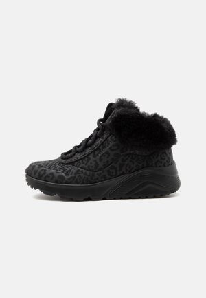 Sort højt sneakers med leopardprint, tyk sål og sort kunstpelskrave vist fra siden på en ensfarvet baggrund.