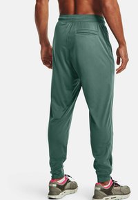 Zelené sportovní kalhoty s tapered designem, elastickým pasem a detailem na zadní kapse. Hladká, lehká tkanina.