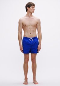 Șort de baie albastru, cu talie elastică și șnur de ajustare. Confecționați dintr-un material ușor, au o textură netedă și dungi laterale.