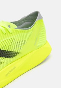 Neonskoro žute tenisice za trčanje s mrežastim gornjim dijelom, crnim detaljima i svijetlosivim ovratnikom. Imaju LIGHTSTRIKE PRO amortizaciju.