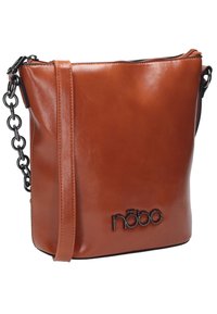 Brązowa skórzana torba crossbody o gładkiej fakturze, z czarnym łańcuszkiem jako paskiem oraz tłoczonym logo z przodu. Zamknięcie na zamek błyskawiczny u góry.