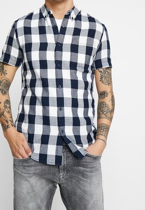Camicia a maniche corte con bottoni in pattern a quadri blu navy e bianco, dotata di taschino sul petto e dettagli del colletto a contrasto, realizzata in tessuto a trama.