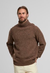 Brauner, grober Strickpullover mit hohem, geripptem Kragen. Verfügt über eine gesprenkelte Textur und leicht fallende Schultern. Einfaches Design, lässige Passform.