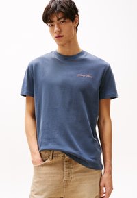 Navy bomull t-skjorte med rund hals og korte ermer. Har liten rosa "Tommy Jeans" logo ved brystet. Løs passform.