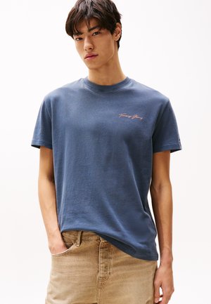 Temno modra bombažna majica s kratkimi rokavi in okroglim izrezom. Na prsih je majhen roza logo "Tommy Jeans". Prijetna prileganje.