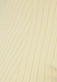 Tissu tricoté de couleur jaune clair présentant une texture côtelée verticale, avec des coutures fines créant un motif doux et subtil.