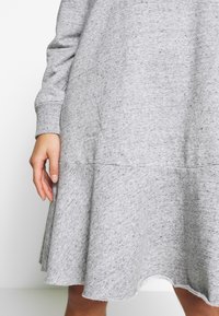 Robe-sweat en tricot gris avec des manches longues et un ourlet évasé. Possède une texture douce et un motif subtilement mélangé tout au long.