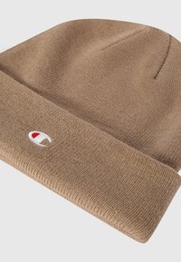 Gorro de punto marrón con puño doblado, que presenta un pequeño logo con un acento rojo. Fabricado con material texturizado.