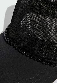 Čierna šiltovka s vrchnou časťou z oka a pevným čiernym šiltom. Má korálikovú ozdobu a vyšité logo na prednej strane. Celkovo textúrovaná tkanina.