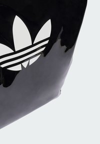 Black glossy bag featuring a large white Adidas trefoil logo and three white stripes. Smooth texture with a compact rectangular shape.