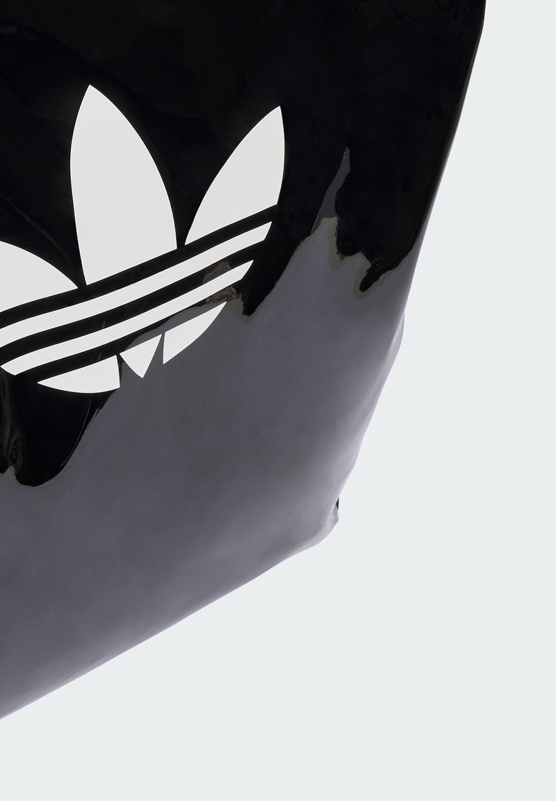 Bolsa negra brillante que presenta un gran logo trefoil blanco de Adidas y tres franjas blancas. Textura suave con forma rectangular compacta.