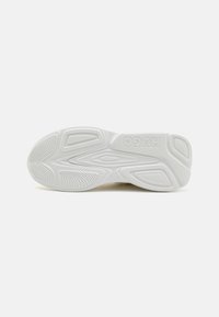 White sneaker sole featuring textured patterns, curved grooves, and raised accents. "HUGO" logo embossed on the heel. Flexible design.