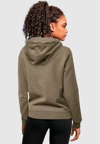Haut à capuche en mélange de coton vert olive avec poche kangourou, poignets et ourlet côtelés. Il dispose d'une capuche avec cordon de serrage et d'une texture douce.