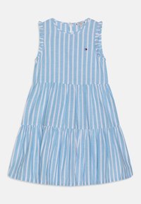 Světle modré šaty bez rukávů s bílými vertikálními pruhy, s vícevrstvou sukní, řasenými zdobeními na rukávech a malým vyšitým logem.