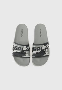 Gray slide sandals featuring a camouflage strap with “REPLAY MILANO” in bold black letters. Soft rubber material; flat, open-toe design.
