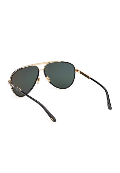 Lunettes de style aviateur avec montures en métal doré, branches noires et verres teintés vert foncé reposant sur une surface blanche.