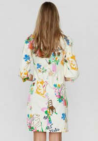 Rochie cu mânecă scurtă din material crem, cu imprimeuri abstractecolorate, inclusiv flori și motive artistice, cu croială dreaptă și croială lejeră.