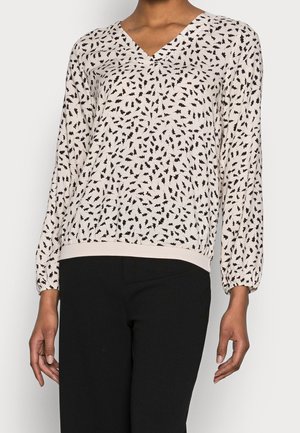 V-halsblouse in lichtbeige stof met zwarte blaadjespatronen, lange mouwen met elastische manchetten en een effen gekleurde tailleband.