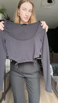 Čierny krátky top s dlhým rukávom, textúrovaným vzorom, zaobleným výstrihom a šnúrkou na spodnej časti. Hladká tkanina s jemnými detailmi.