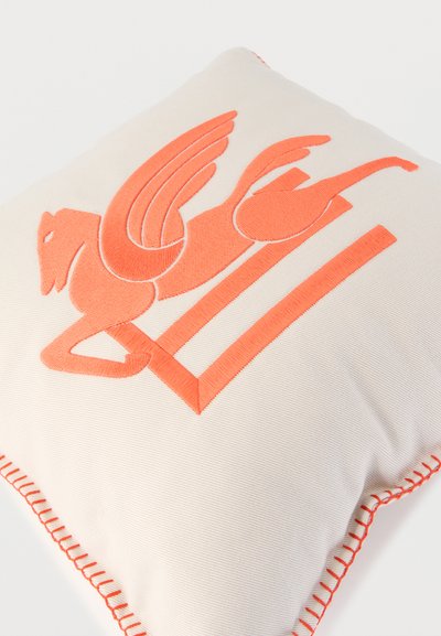 Coussin en tissu crème avec cheval ailé brodé orange et bordure cousue orange.