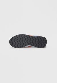 Melnas gumijas kurpju zole ar zigzag rakstu, kas ir ar teksturētu virsmu un Reebok logotipu. Augšpusē redzami arī citi toņi.