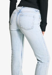 Svijetloplave, visokog struka traperice ravnog kroja. Imaju dva stražnja džepa i suptilno izbljeđivanje. Izrađene su od trapera s glatkom teksturom.