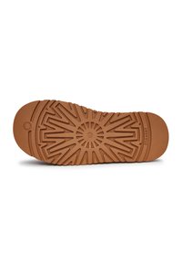 Semelle de chaussure en caoutchouc brun avec une surface texturée et décorée, présentant des rainures radiales et un emblème circulaire vers le centre.