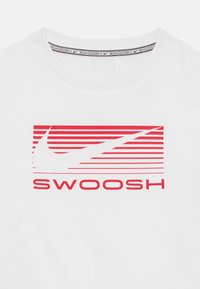 Balts sporta krekls ar sarkanu horizontālu svītru grafiku un tekstu "SWOOSH". Tam ir apaļa kakla izgriezums un gluda, viegla auduma struktūra.