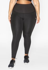 Zwarte high-waisted legging gemaakt van glad, rekbaar materiaal. Beschikt over een brede tailleband en een slim fit silhouette, ideaal voor actieve kleding.