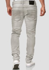 Lichtgrijze denim jeans met een slim fit, vijf zakken ontwerp en een zwart merkpatch op de tailleband. Inclusief subtiele stiksel details.