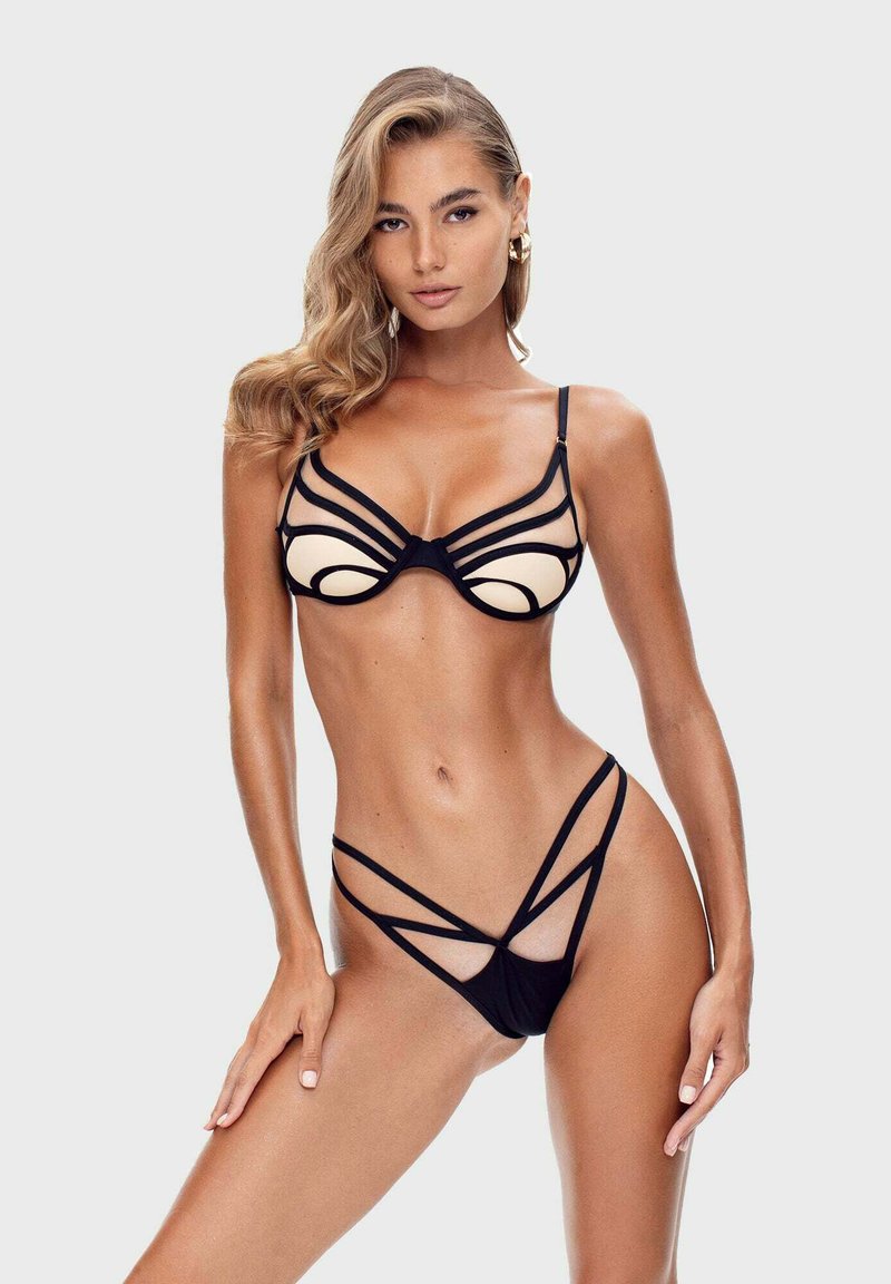 Schwarzes und hautfarbenes Bikini mit einem trägerloses Design, das mehrere Riemen im BH und im Slipper aufweist und geometrische Formen sowie Kontraste hervorhebt.