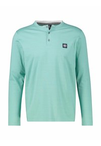 Long-sleeve mint green cotton shirt with a henley neckline, two buttons, and a navy logo patch on the left chest. Smooth texture.