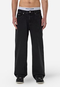 Sorte denim jeans med en afslappet pasform, der har en knaplukning, fem lommer og et kontrastfarvet hvidt bælte med mærket "PEGADOR."