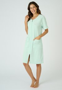 Accappatoio verde menta con zip, realizzato in tessuto morbido, con maniche corte, due tasche anteriori, uno spacco frontale e un dettaglio a conchiglia ricamato.