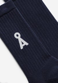 Marineblaue gerippte Socken mit weißem, besticktem Logo. Sie zeichnen sich durch eine glatte Textur und eine Standard-Sockenform aus, die für Komfort und Passform entwickelt wurde.