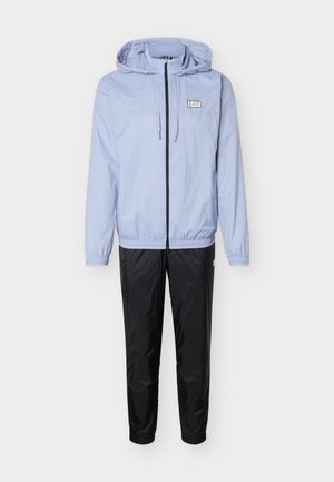 Svetlomodrá bunda s kapucňou, predným zipsom a logom, v kombinácii s čiernymi zúženými nohavicami na bielom pozadí.