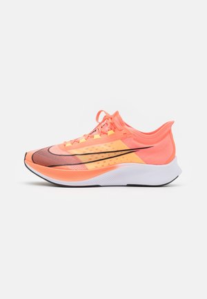 Chaussure de sport rose avec une tige en mesh léger, des accents noirs, une semelle intermédiaire texturée et une semelle extérieure blanche. Dispose de lacets colorés et d'un design dynamique.