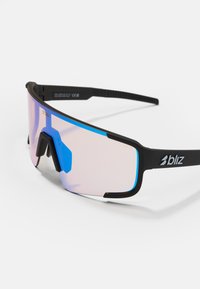 Czarne sportowe okulary przeciwsłoneczne z dużą różową soczewką, niebieskimi akcentami i płaskim szczytem. Posiadają regulowany nosek i teksturowane zauszniki.