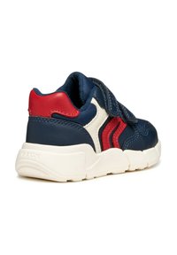 Sneaker in pelle blu con dettagli rossi e crema, dotato di un cinturino in Velcro e superficie texture. Suola bianca spessa per supporto.