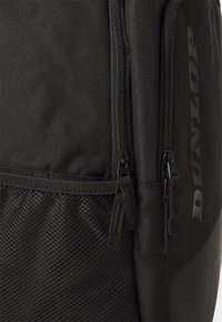 Schwarzer Rucksack aus strapazierfähigem Stoff, mit zwei Reißverschlüssen, einem Netzfach und einem bedruckten Logo, im eleganten, strukturierten Design.
