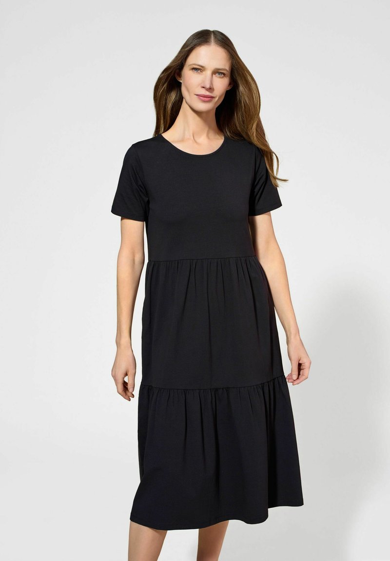 Czarna bawełniana sukienka z krótkimi rękawami, okrągłym dekoltem i warstwowym designem. Miękka tekstura z płynącą sylwetką, długość do kolan.